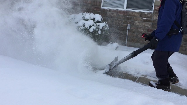 Snow being scraped from the side walk with high air flow