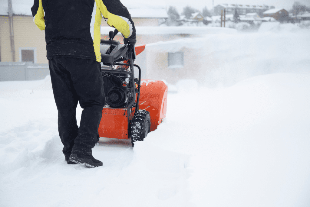 A man pushes a snow blower to clear out snow