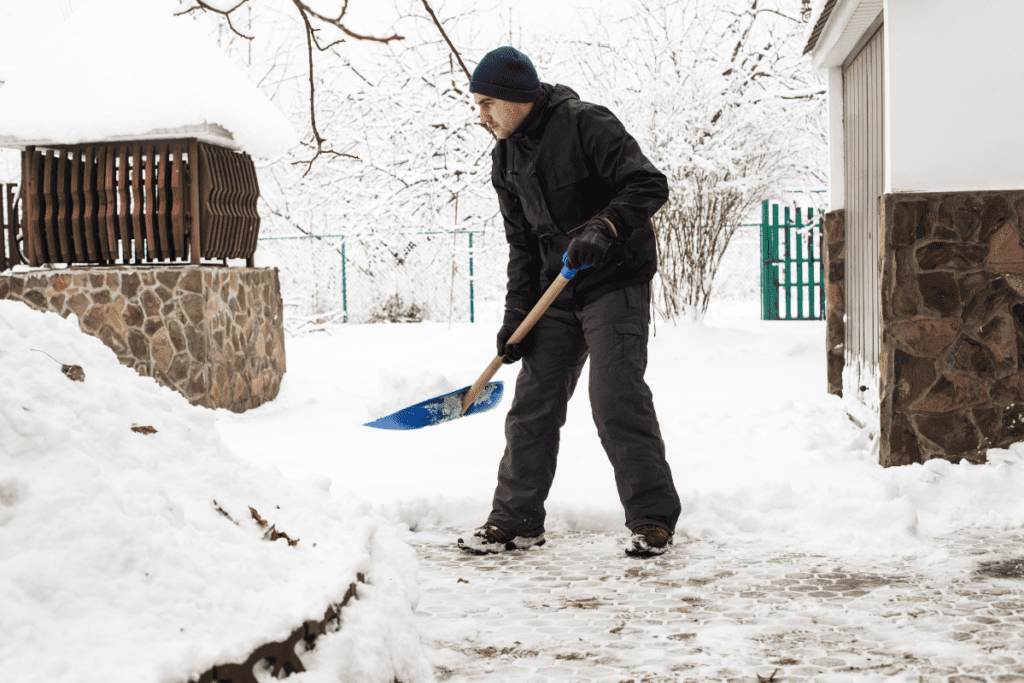 A man shoveling snow in front of a house