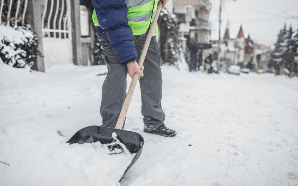 Man removing snow with a shovel outside on the street.