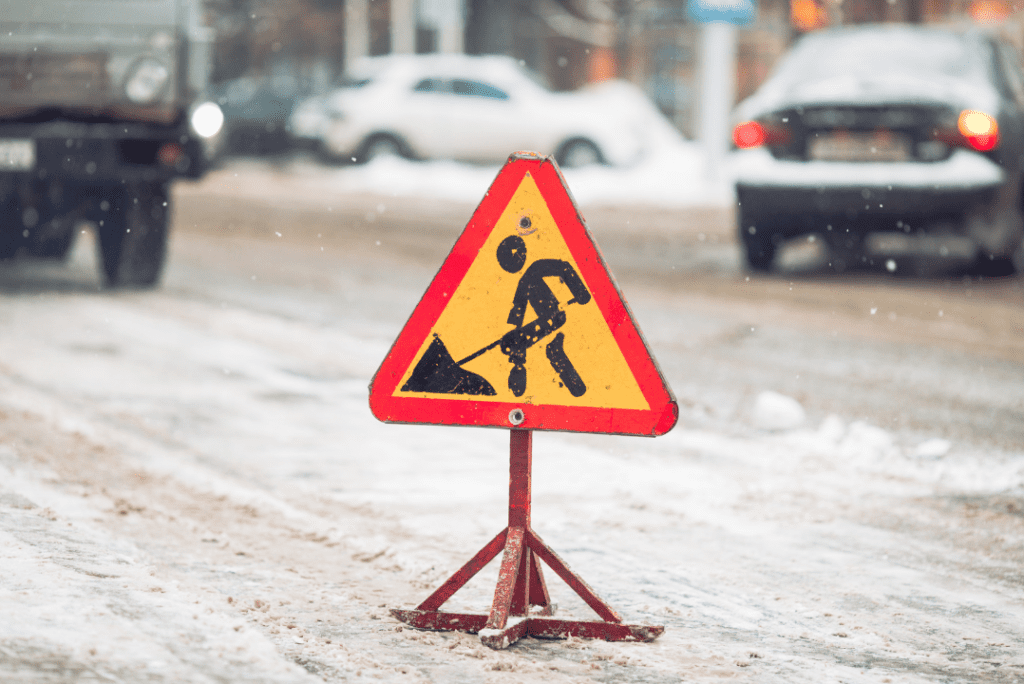 A warning sign placed on a busy road to protect snow removal pros