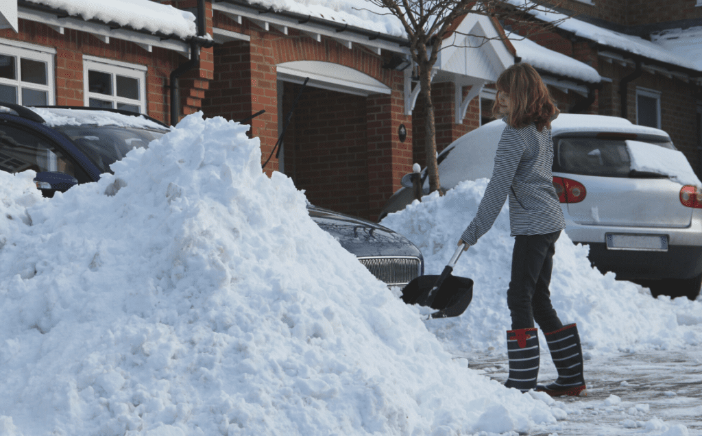A woman piles snow beside her driveway