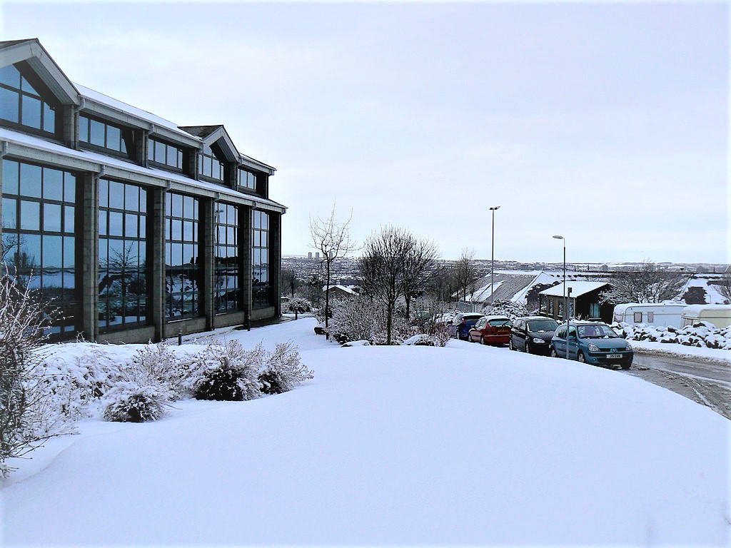 Snow covers the lawn outside an office building