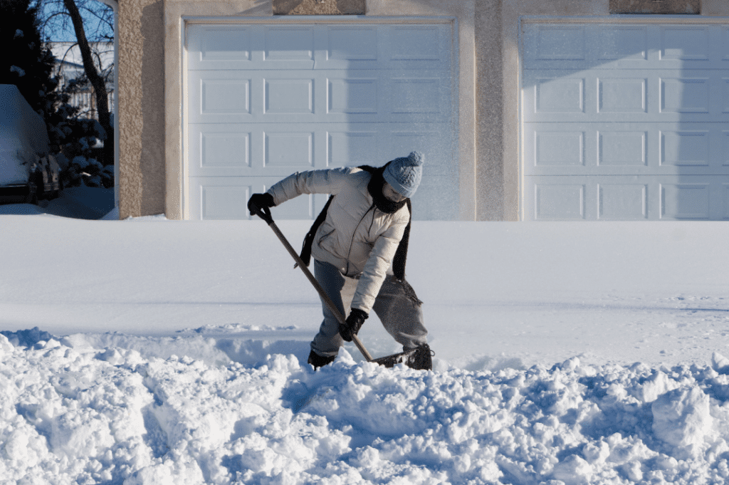 A woman shoveling a pile of snow out of her driveway at home