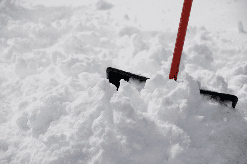 A snow shovel in large pile of snow