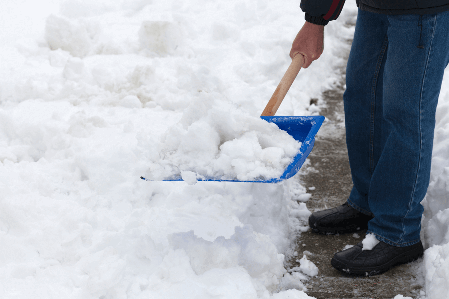 A man using a shovel to clear out snow from a pathway
