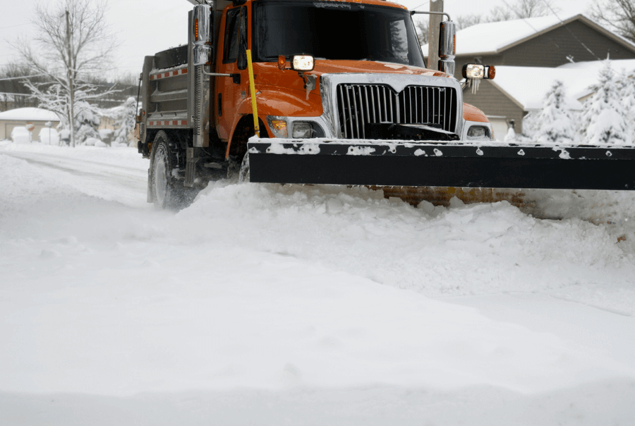A plow truck clearing the snow on village streets
