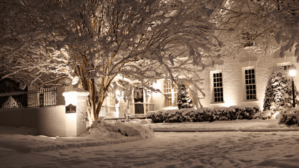 Lights shine on a snow-covered house at night