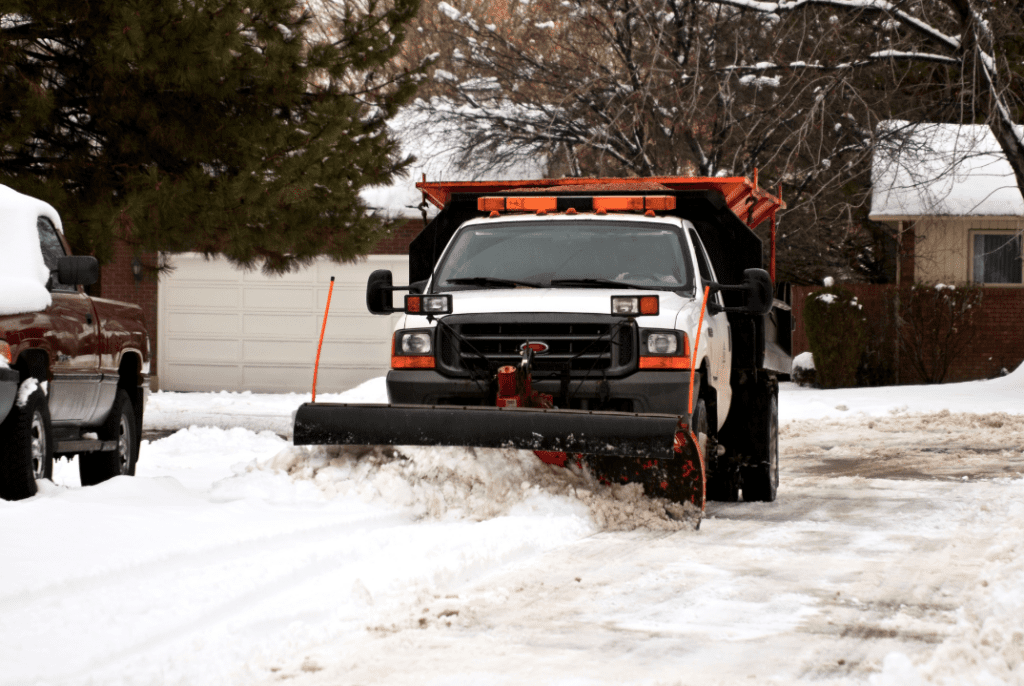 A snow plow truck clearing off a residential street