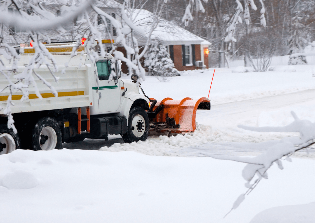 A snow plow pushing snow in a residential area