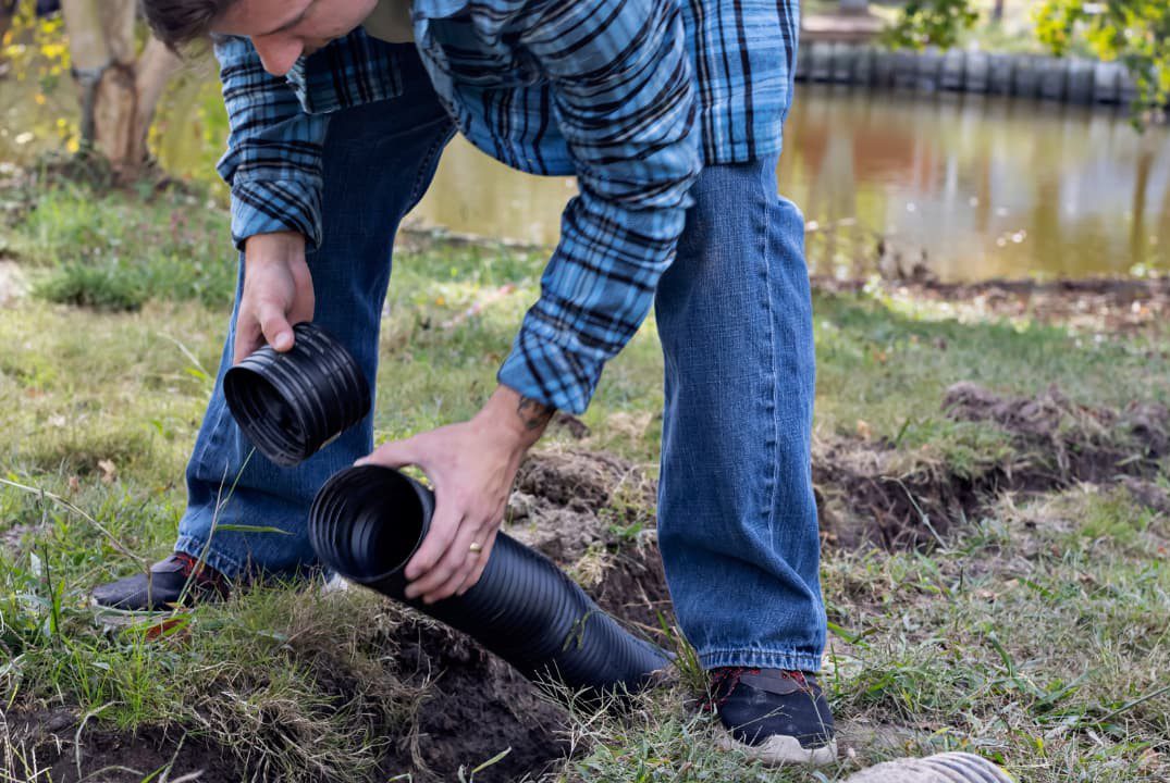 A man installing pipes for a french drain setup