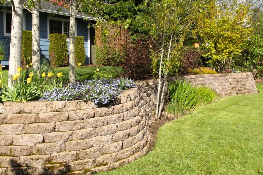 A cobblestone retaining wall in landscaped yard