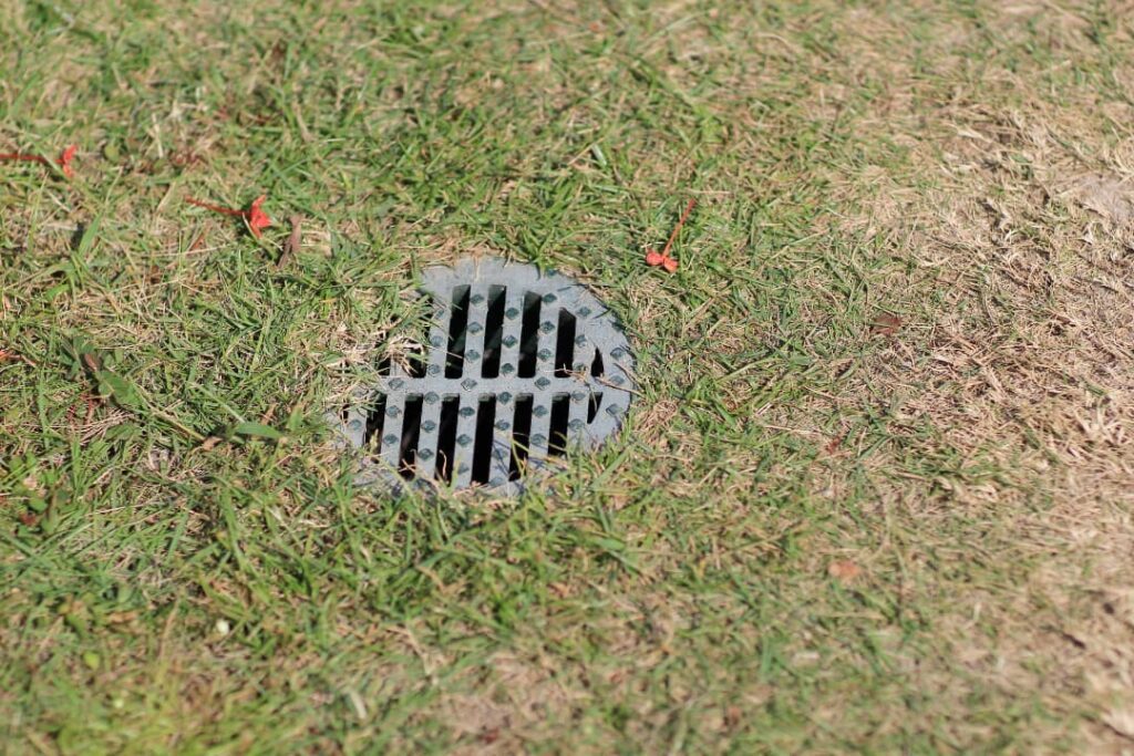 Iron grate of water drain in grass garden in Naperville