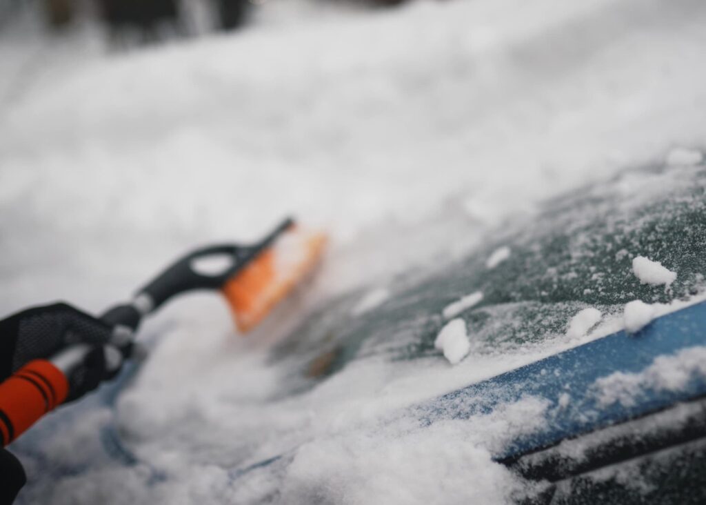 A person removing snow using a small brush