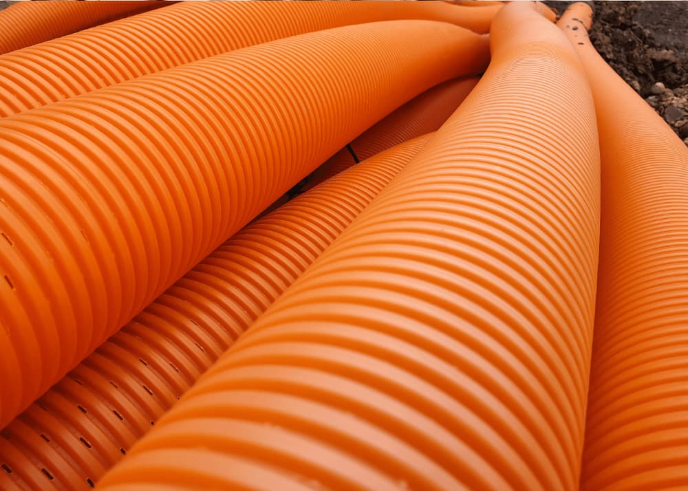 Opt for perforated PVC or corrugated plastic pipes for drainage and avoid using small or non-perforated pipes.