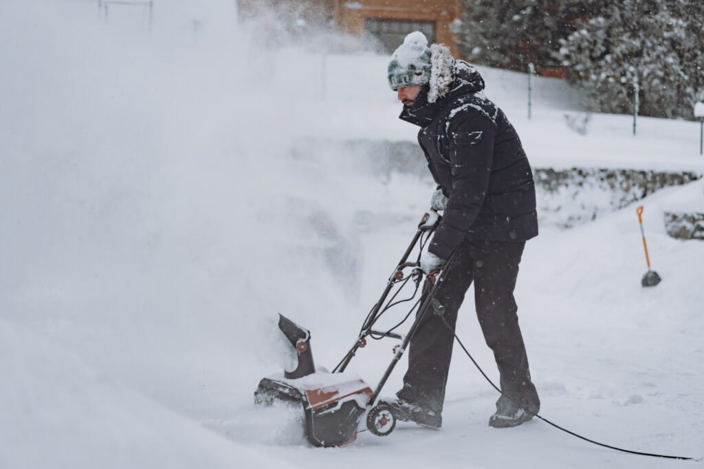 clearing snowdrifts using electric snow blower on snowy winter day