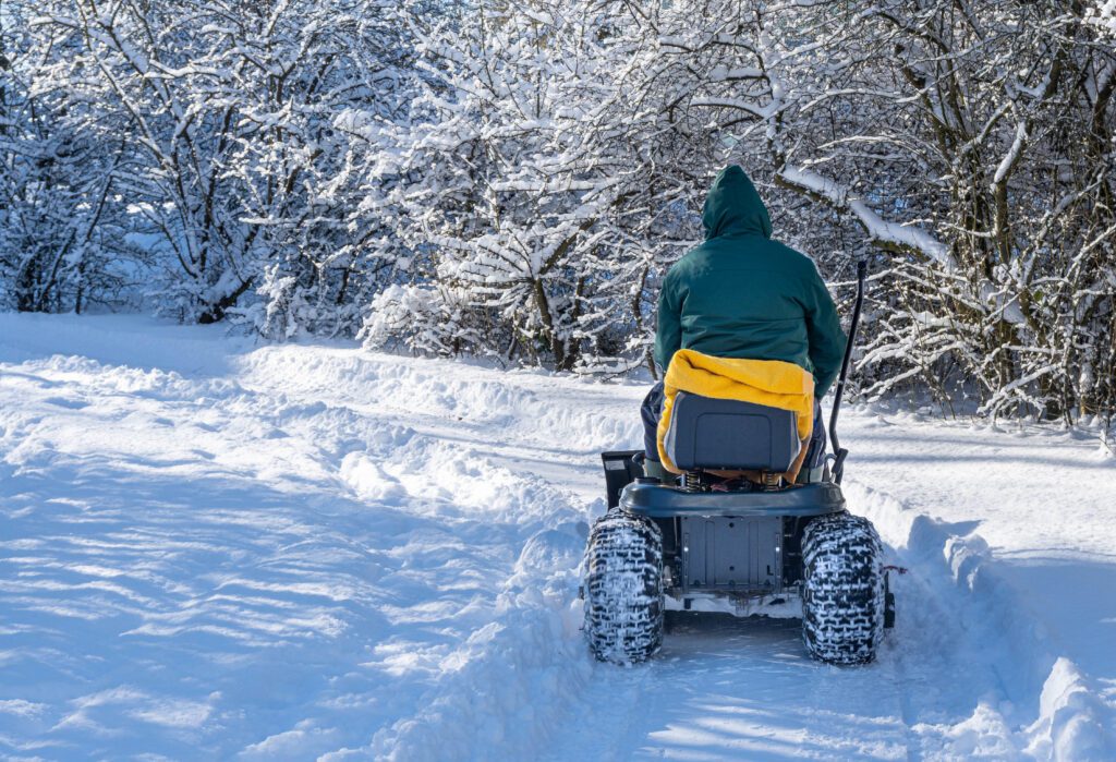 A man riding snow blower clearing a snow-covered field